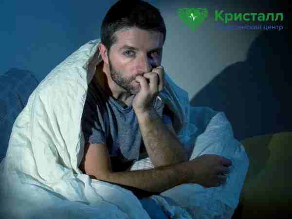 Мужчина сидит на кровати ночью